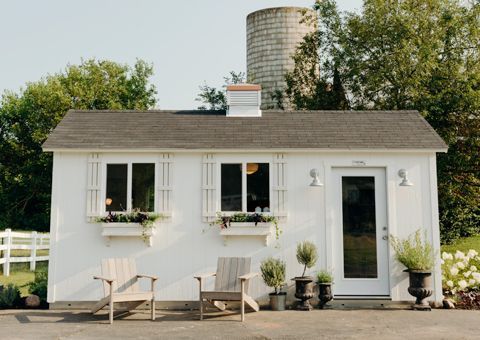 A small white house with a silo in the background.