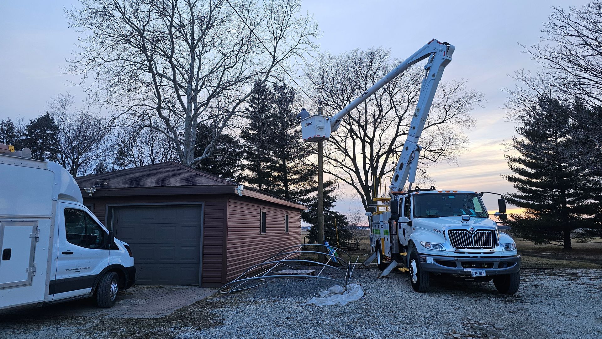 A truck with a crane on top of it is parked in front of a garage.
