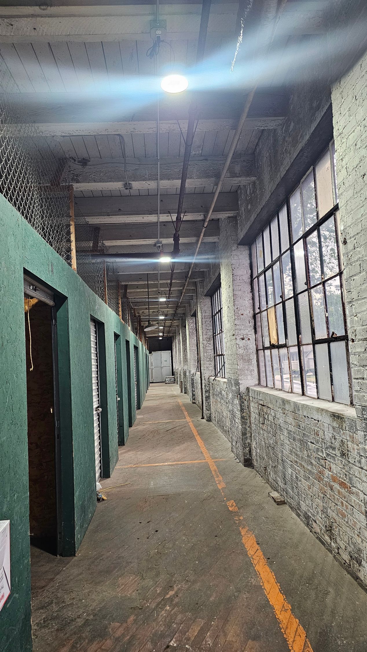 A long hallway in an abandoned building with green walls and a yellow line.