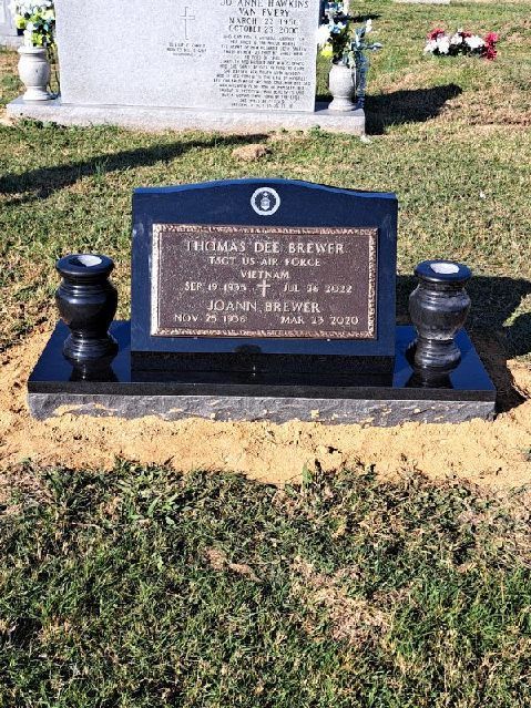 A black gravestone with two vases on top of it in a cemetery.