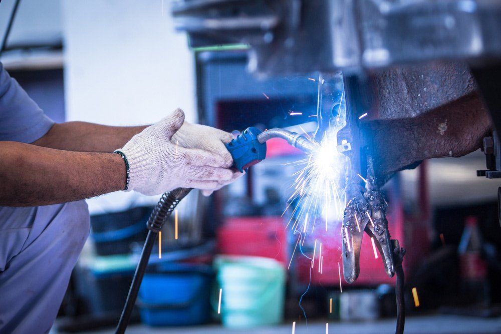 Welder in Safety Gloves Using a Welding Torch, Bright Sparks, Indoors — Mid City Smash Repairs in Dubbo, NSW