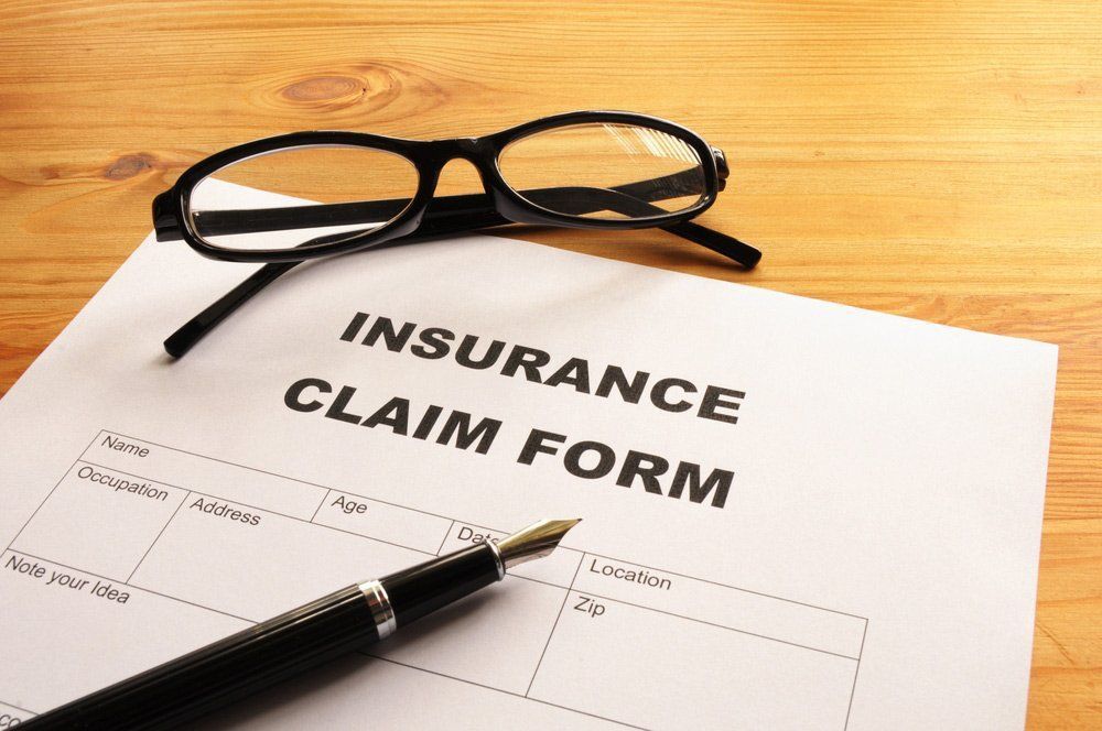 Insurance Claim Form With Pen and Eyeglasses on a Wooden Surface — Mid City Smash Repairs in Dubbo, NSW