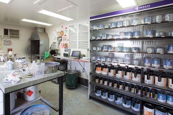 A Paint Mixing Room With a Messy Work Area and a Display of Paint Cans — Mid City Smash Repairs in Dubbo, NSW