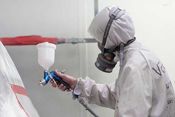 Person in Protective Suit Using a Paint Sprayer in a Workshop — Mid City Smash Repairs in Dubbo, NSW