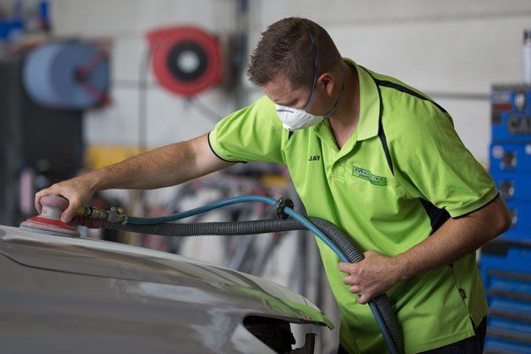 Man Wearing Mask Sanding a Car Panel in a Workshop — Mid City Smash Repairs in Dubbo, NSW