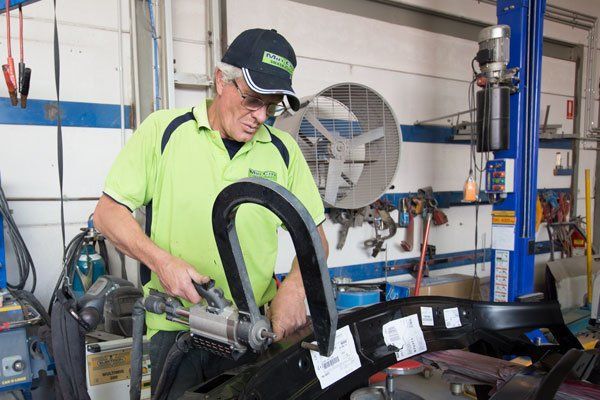 Mechanic in Green Shirt and Cap Using a Tool — Mid City Smash Repairs in Dubbo, NSW