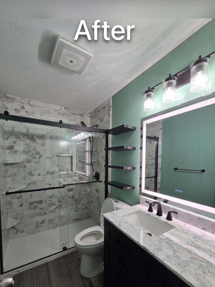 Remodeled bathroom with marble-look shower and vanity, green accent wall, and floating shelves.
