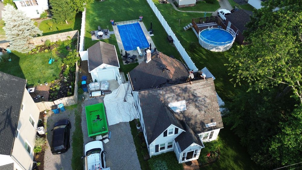 Aerial view of a house with a pool, garage, and a large tarp covering the driveway.