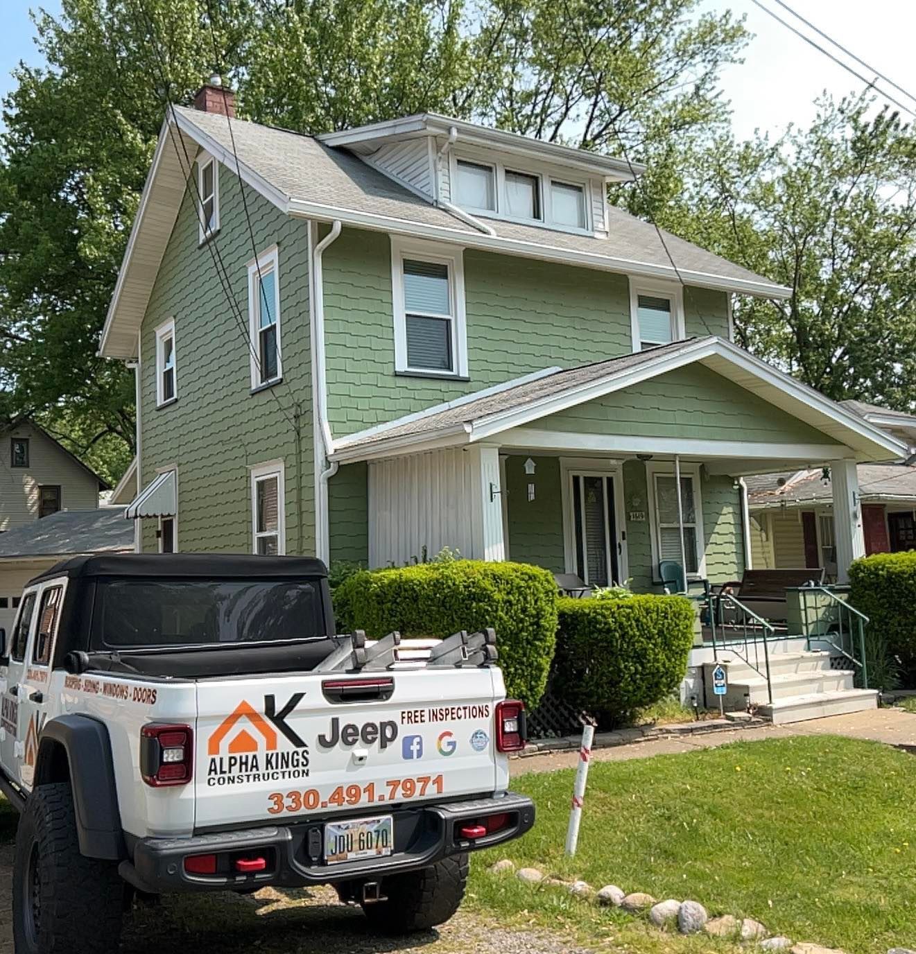 Green two-story house with white trim; a white truck with “Alpha Kings” logo is parked in front.