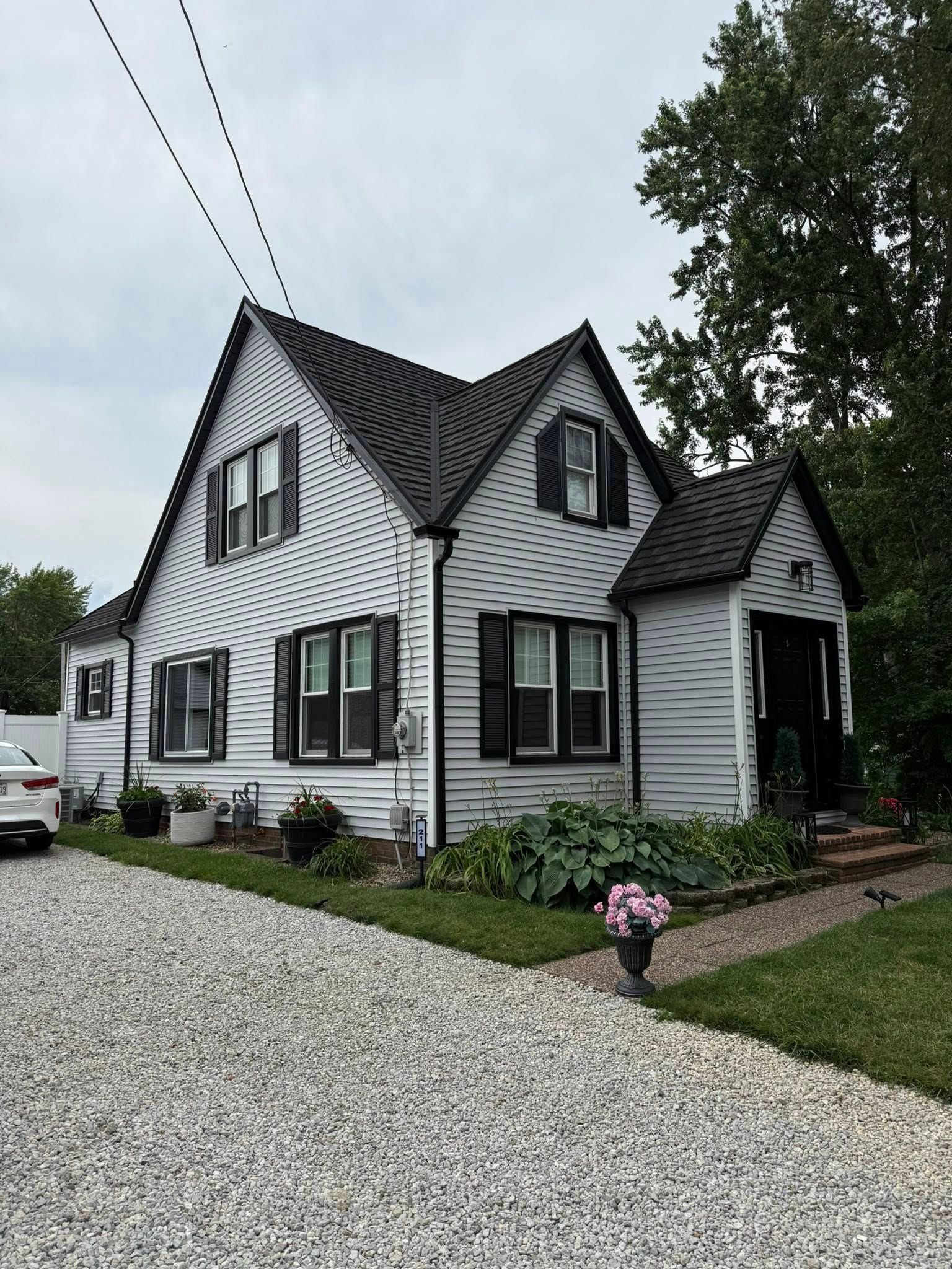 Gray and black house with a gravel driveway and small flower bed.
