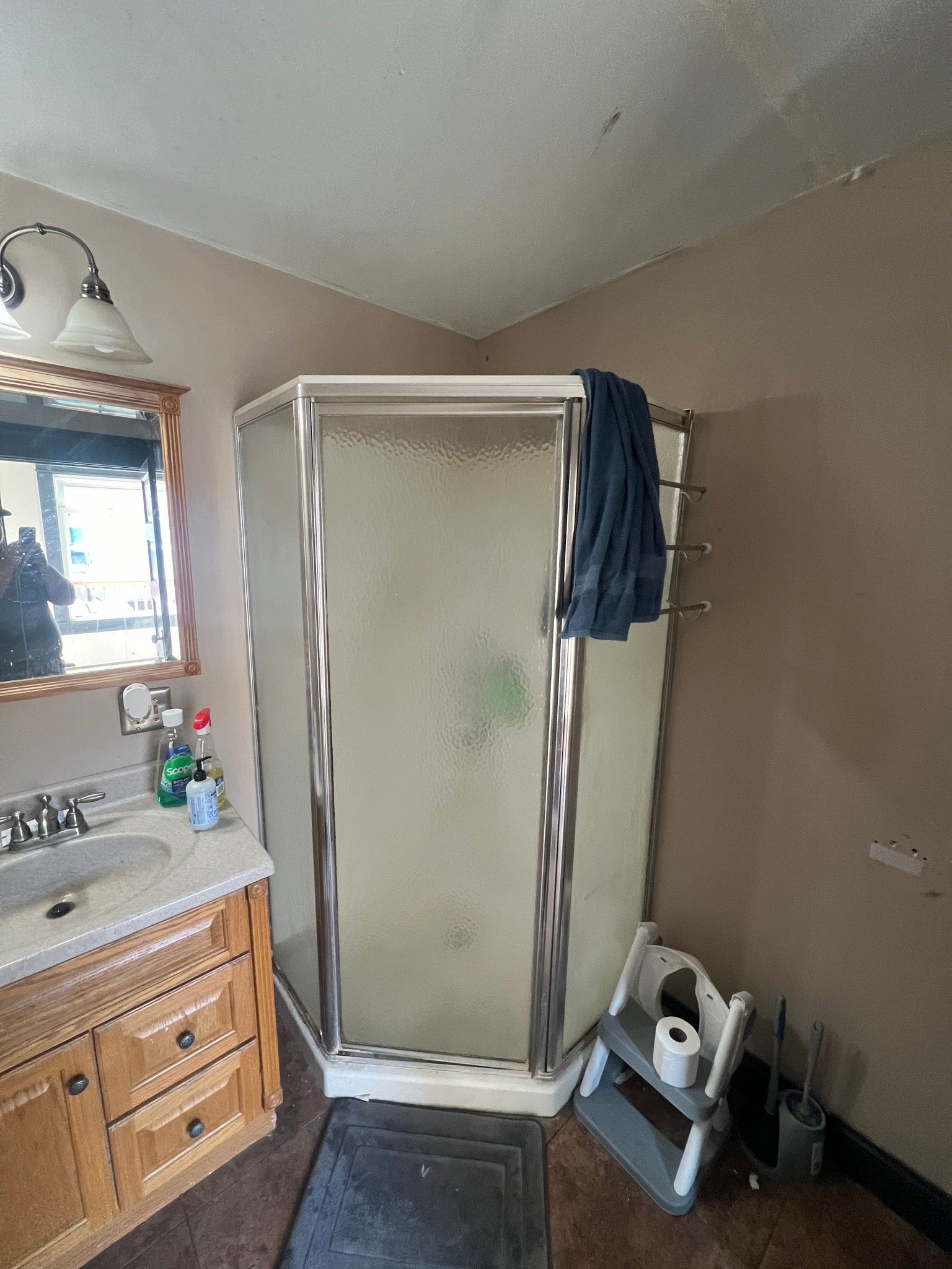 Bathroom with octagonal shower, vanity, and step stool.