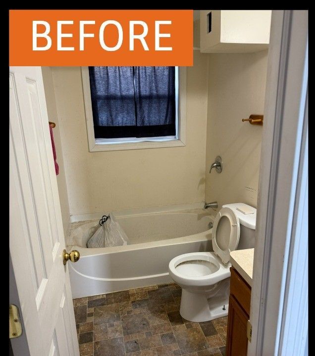 Small, dated bathroom with a tub, toilet, and window. Beige walls, dark curtain.
