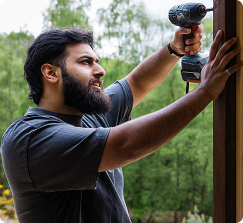 a man with a beard is using a drill on a wall .