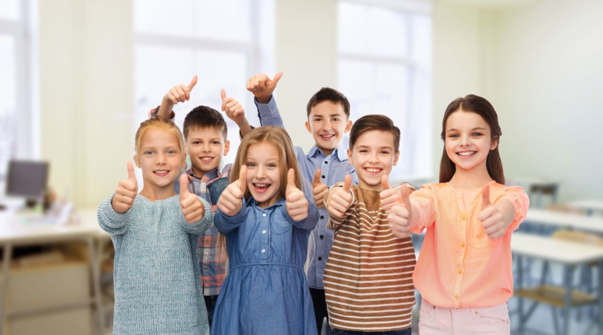 A Group of Children Are Giving a Thumbs Up in a Classroom — Grandma Rosie’s Quality Long Day Care In Wollongong, NSW