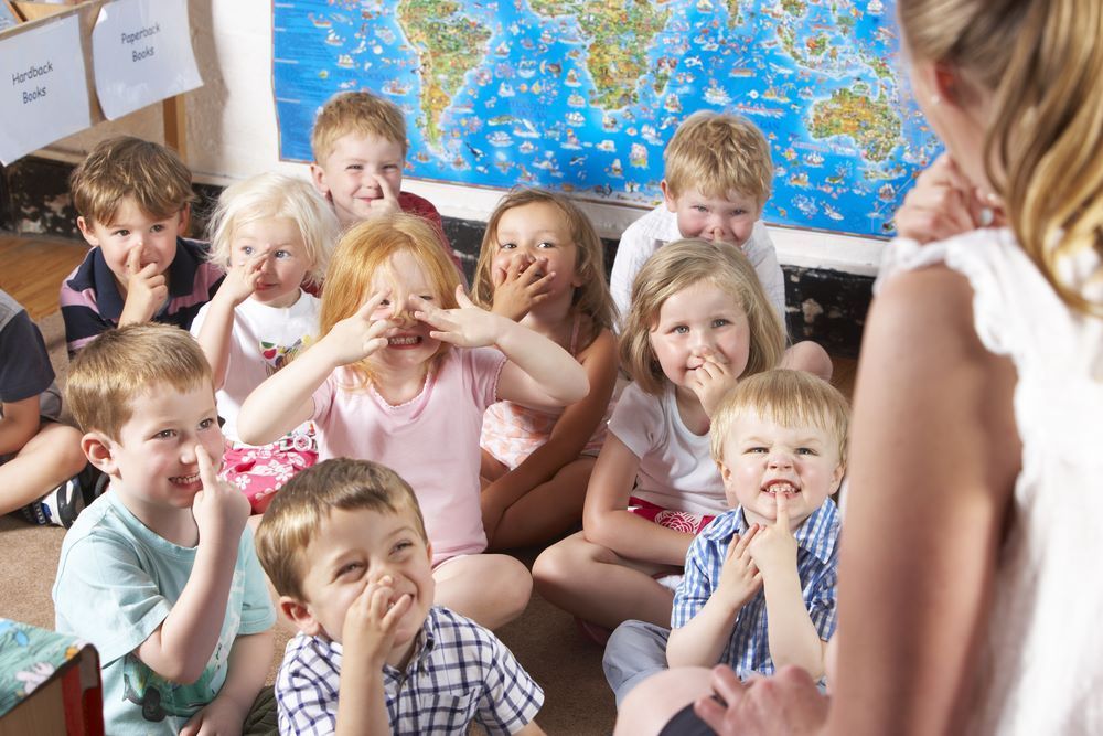 A group of children are sitting on the floor in front of a map of the world — Grandma Rosie’s Quality Long Day Care In Haywards Bay, NSW