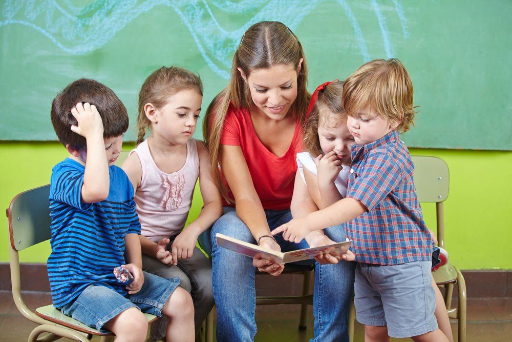 Children And Nursery Teacher Reading Book Together In Kindergarten — Grandma Rosie’s Quality Long Day Care In Wollongong, NSW