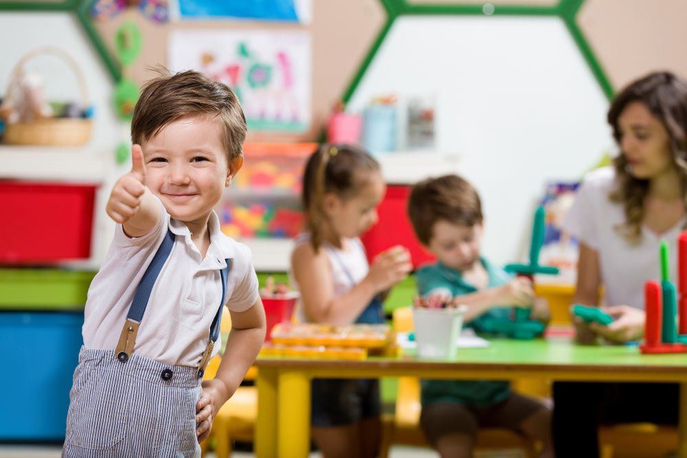 Cute Little Boy Giving Thumbs Up In Classroom — Grandma Rosie’s Quality Long Day Care In Wollongong, NSW