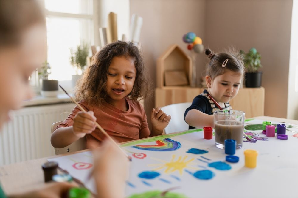 Children Painting Colorful Pictures At A Table During Art Time — Grandma Rosie’s Quality Long Day Care In Wollongong, NSW