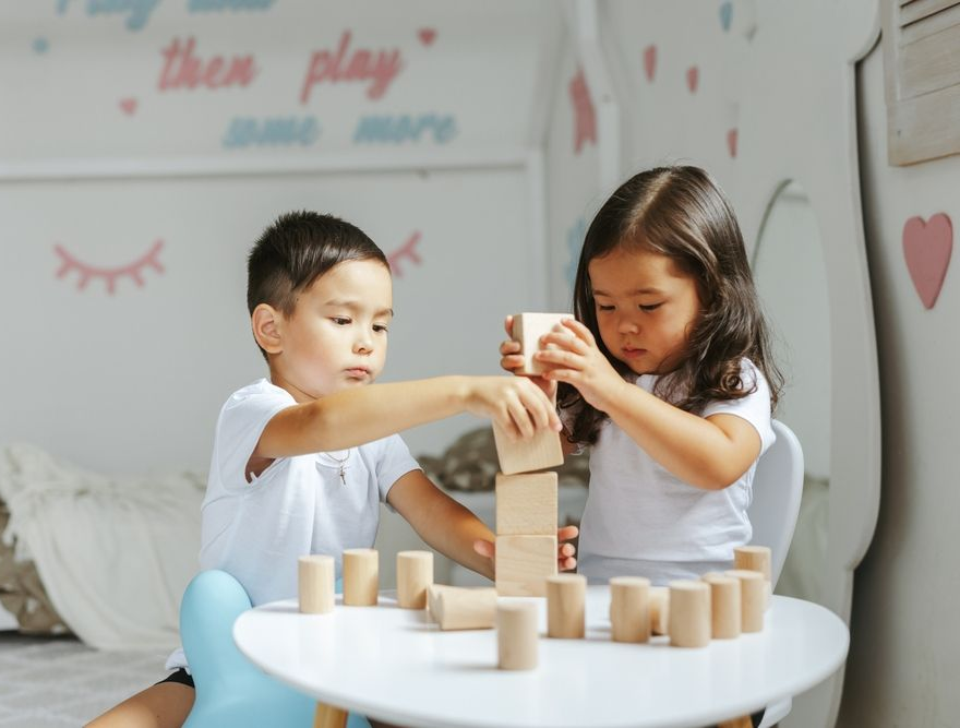 Two Children Stacking Wooden Blocks While Playing Together — Grandma Rosie’s Quality Long Day Care In Wollongong, NSW
