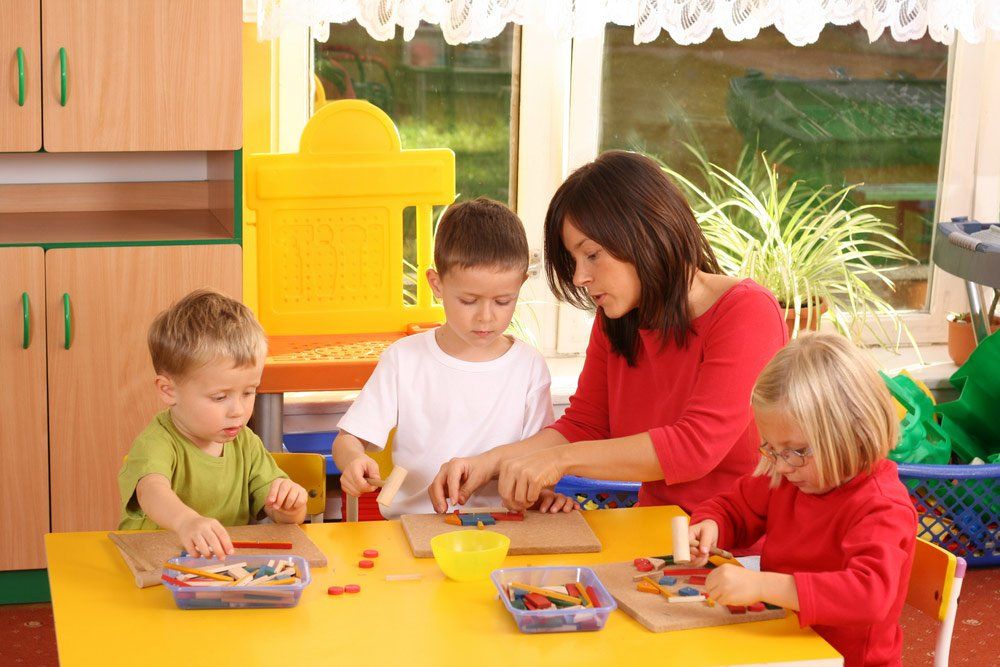 Preschool Teacher And Three Preschoolers Playing With Wooden Blocks — Grandma Rosie’s Quality Long Day Care In Wollongong, NSW