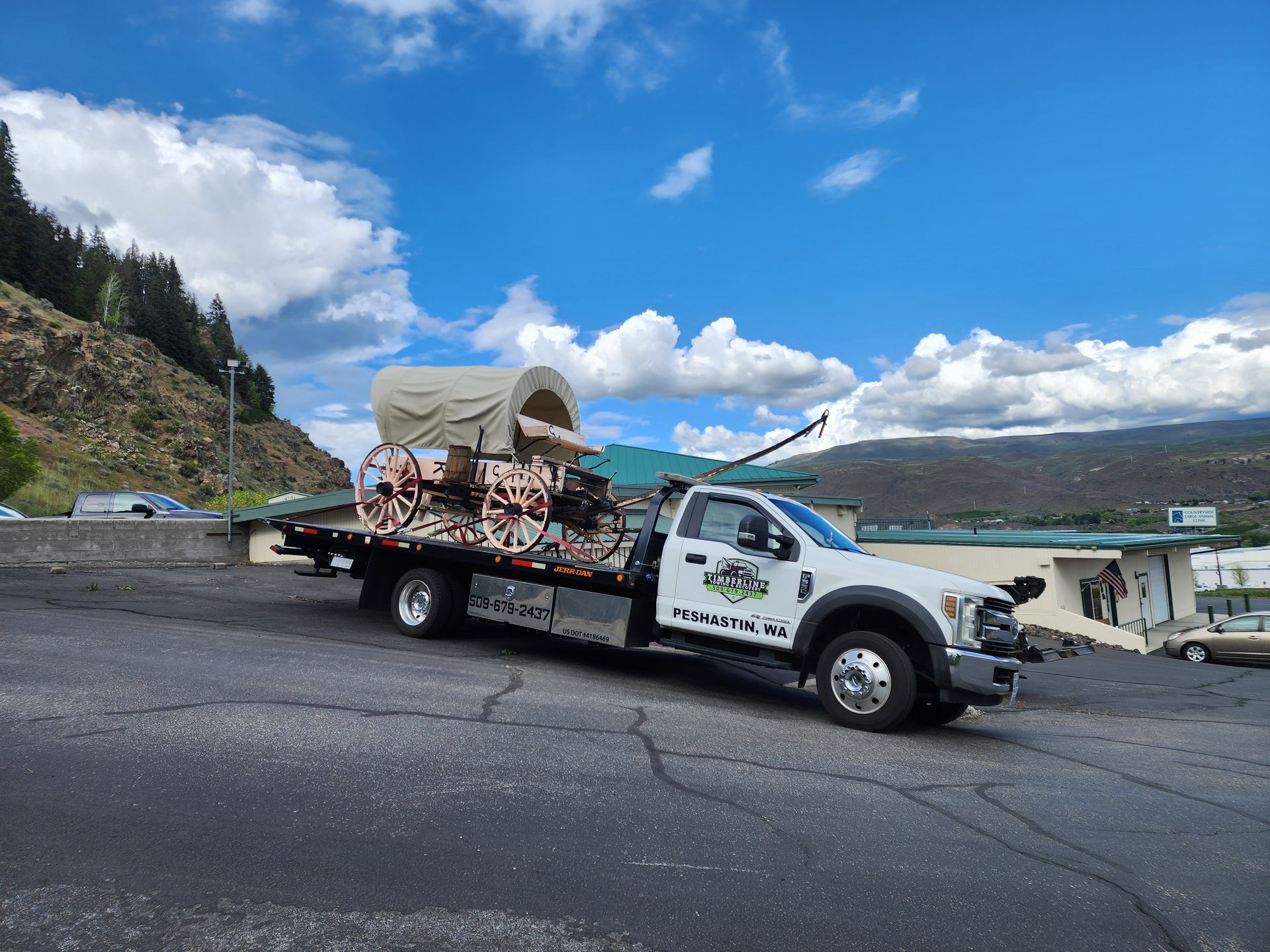 A tow truck is carrying a horse drawn carriage on a trailer.