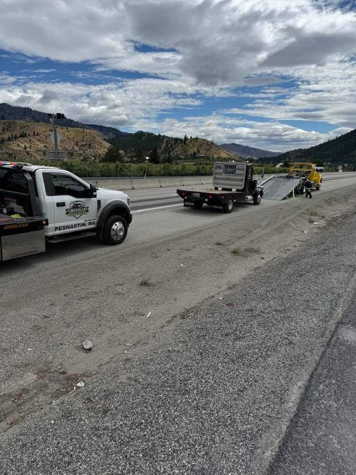 A tow truck is towing a car on the side of the road.