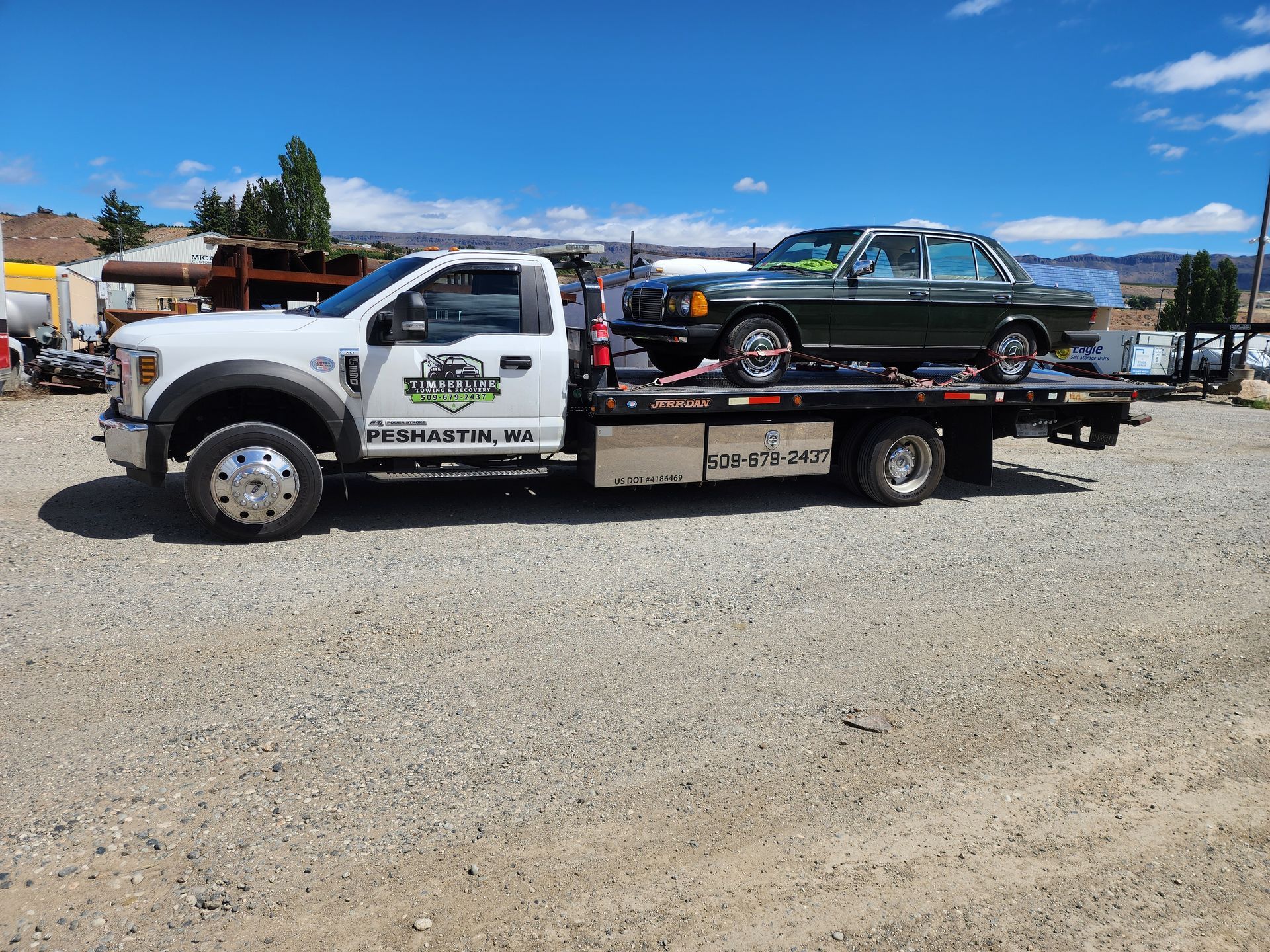 A tow truck is carrying a car on the back of it.