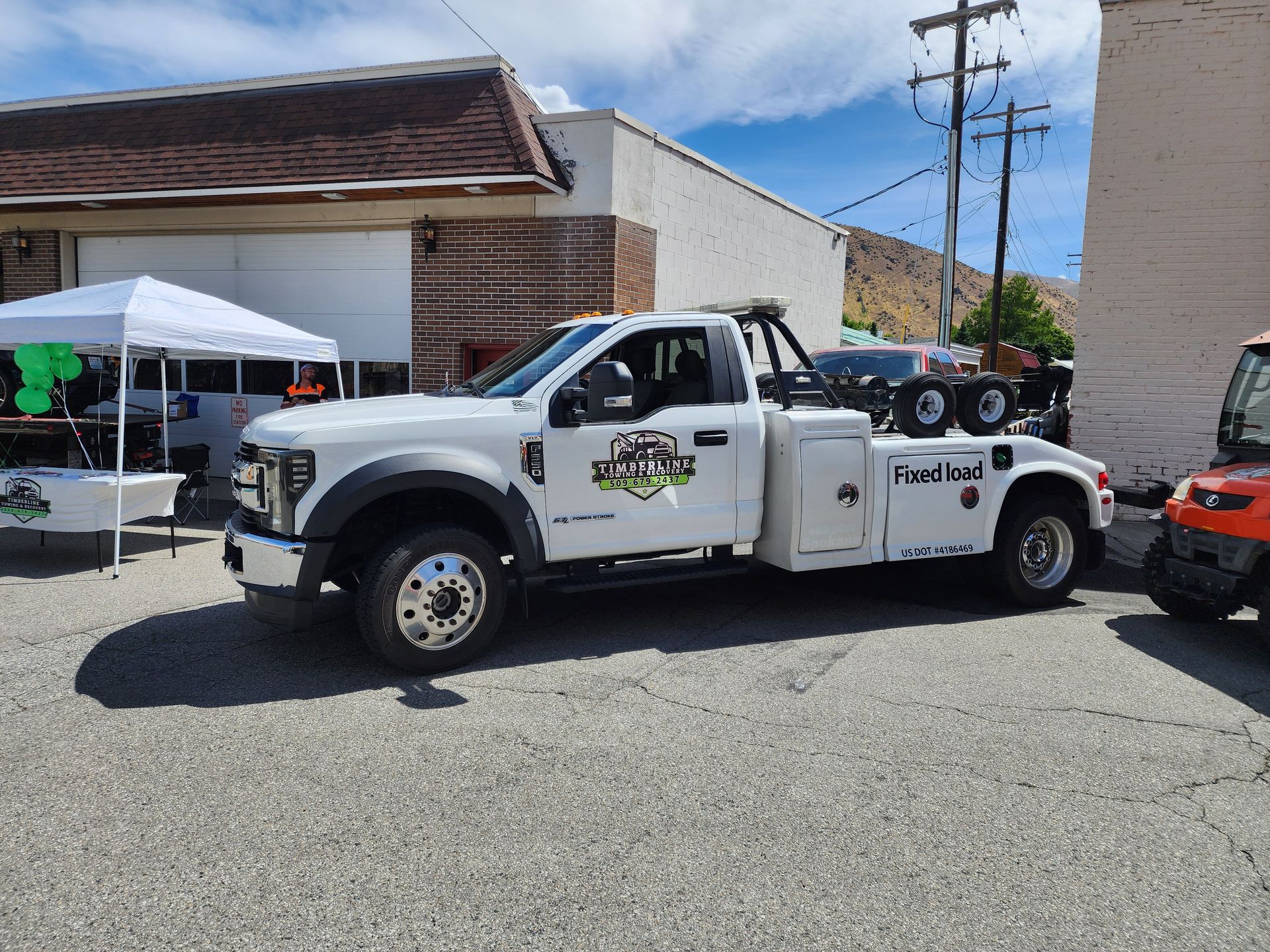 A white tow truck is parked in front of a building.