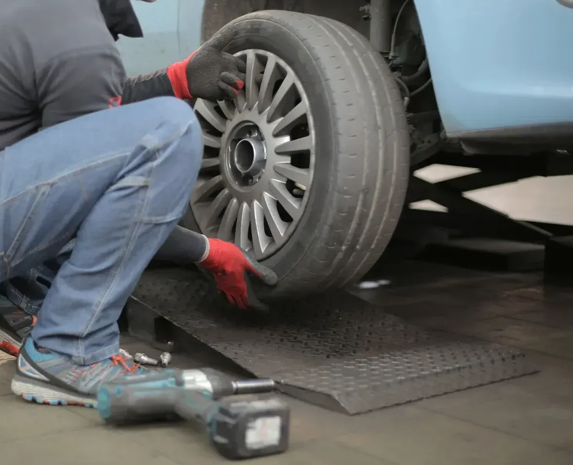 A man is changing a tire on a car with a drill.