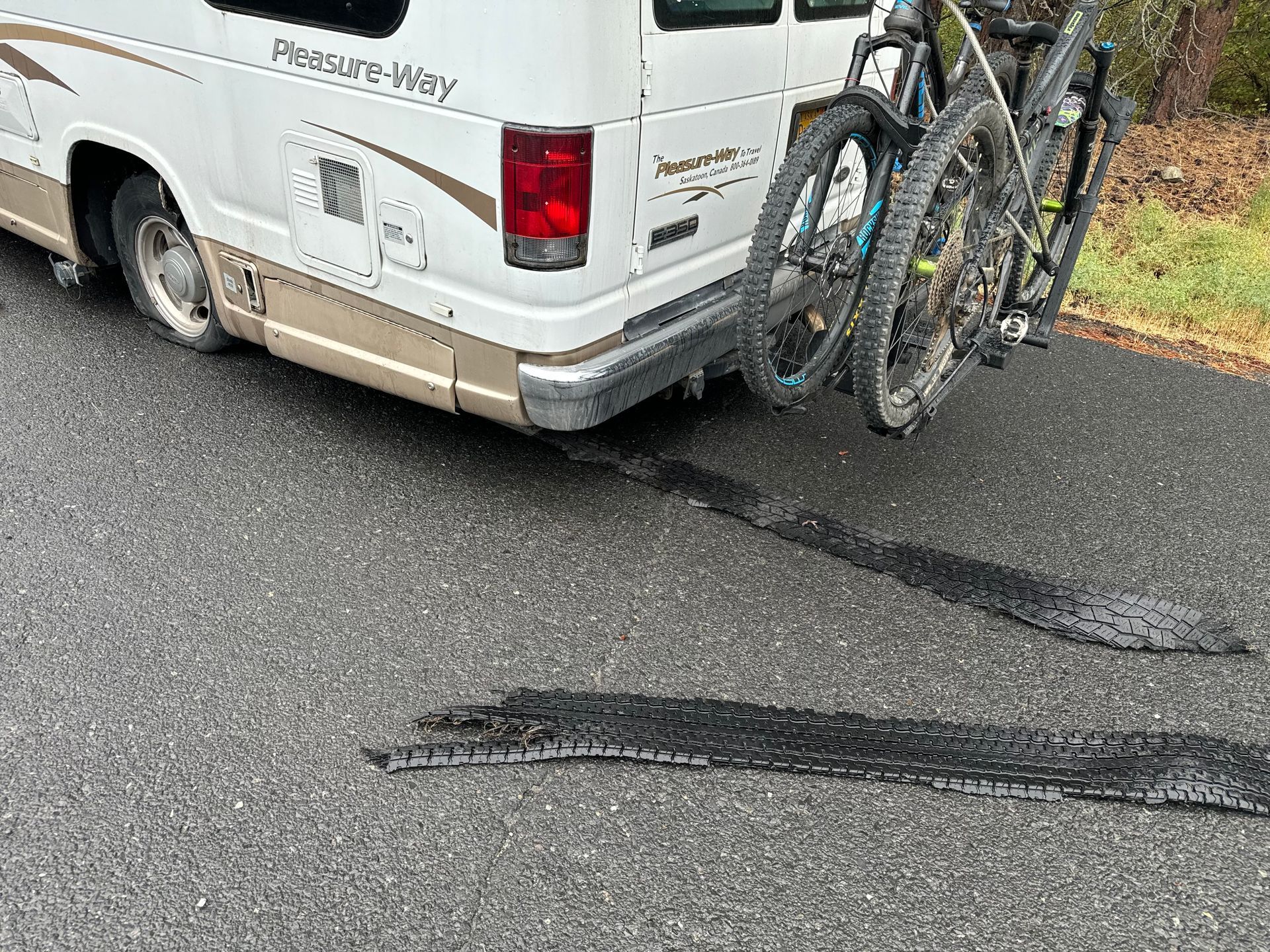 A white van with two bicycles attached to the back of it.