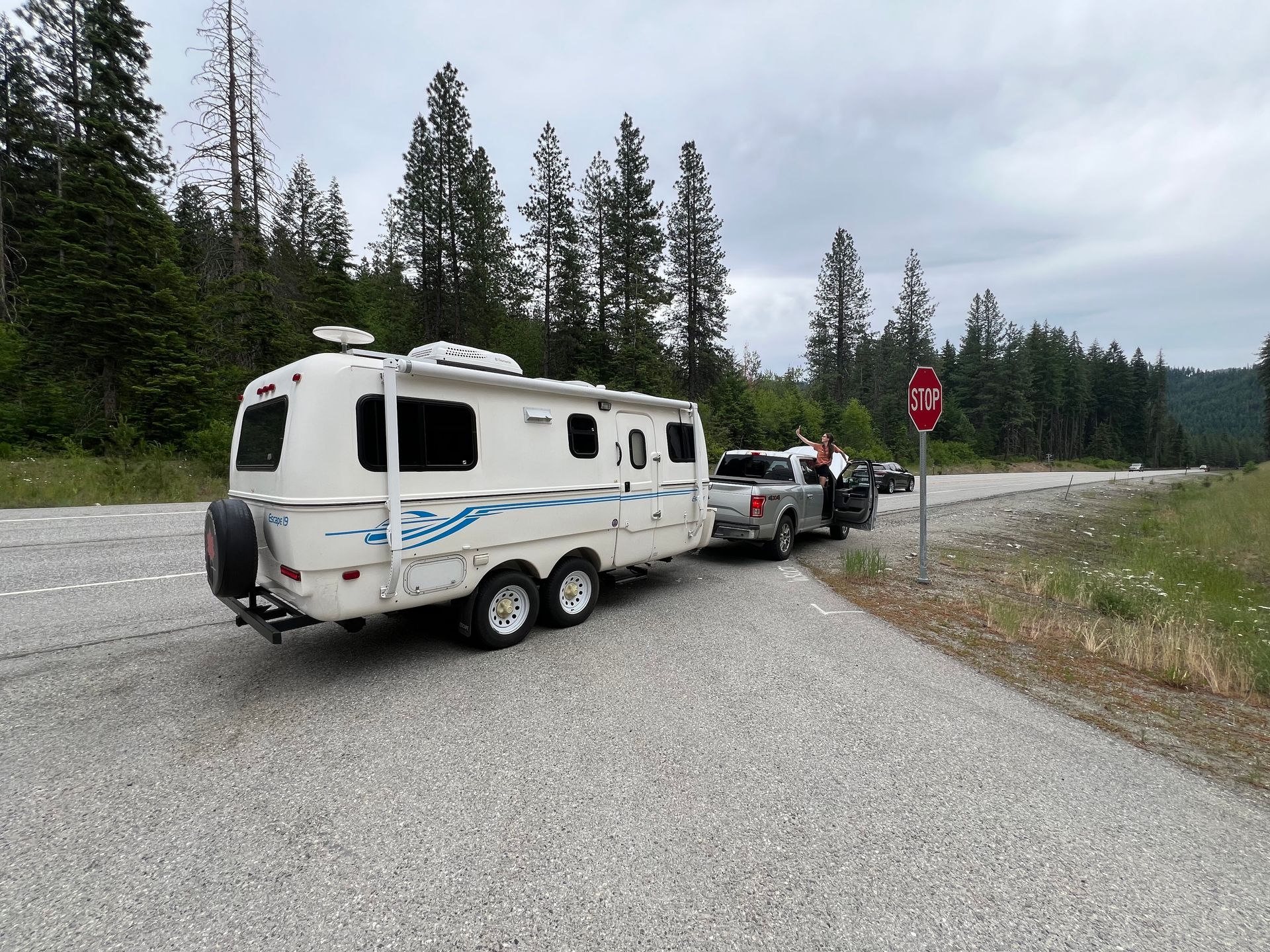 A white trailer is being towed down a road by a truck.