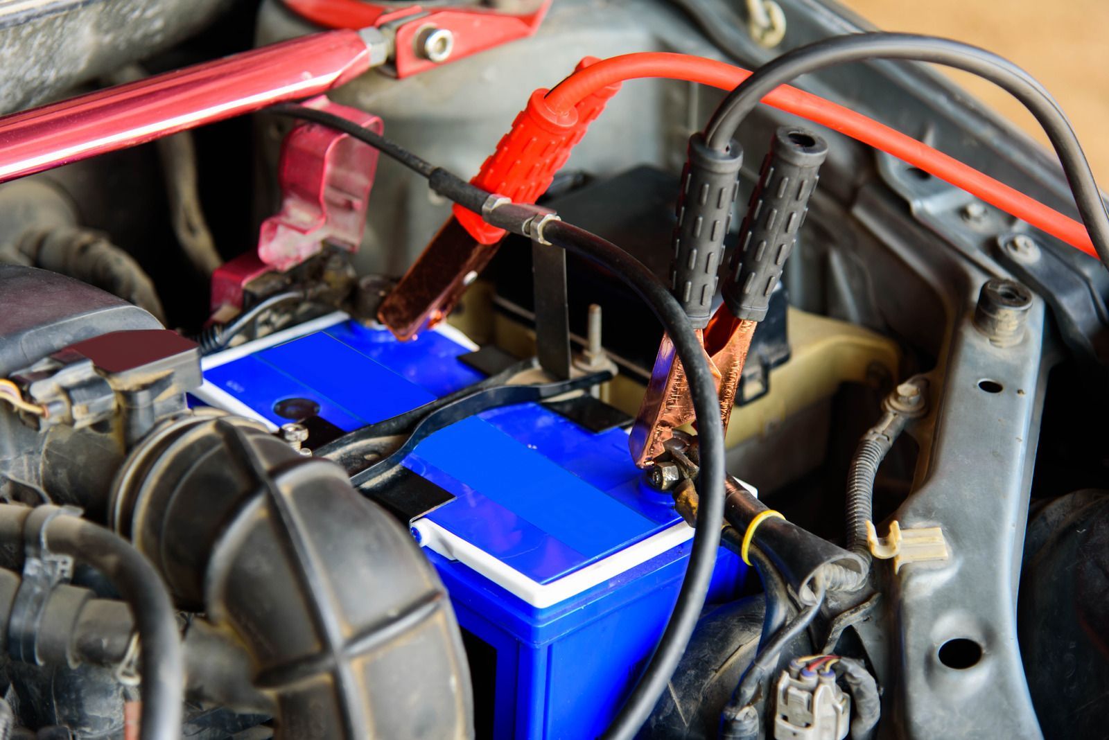 A car battery is being charged with red and black wires.