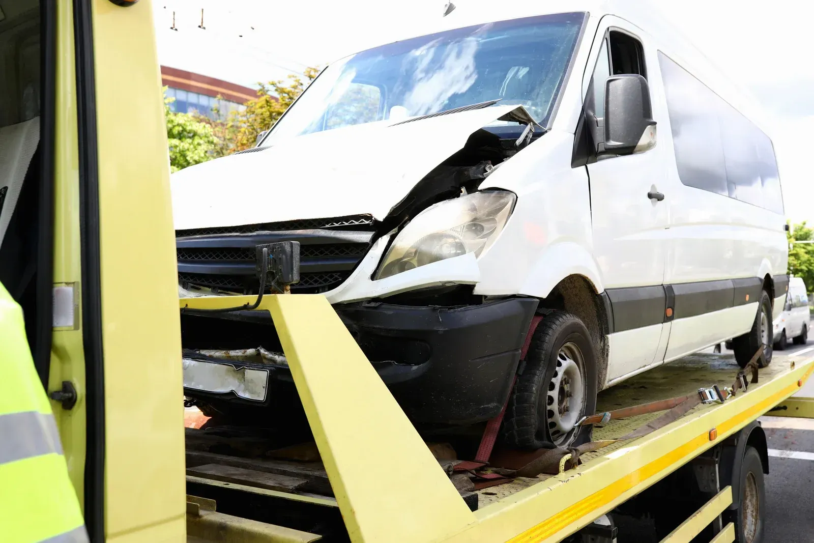 A white van is being towed by a tow truck.