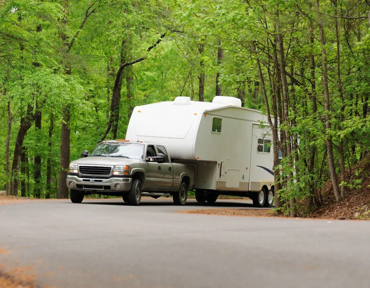 A truck is towing a trailer down a road.