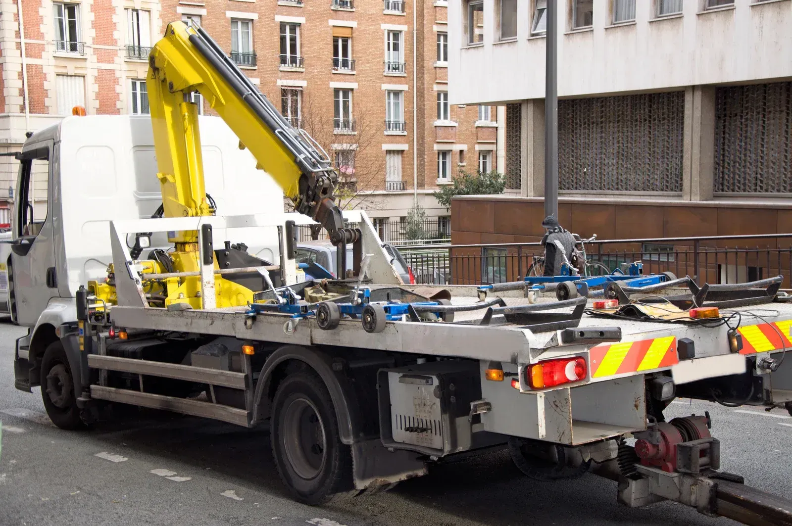 A tow truck with a crane on the back is parked on the side of the road.
