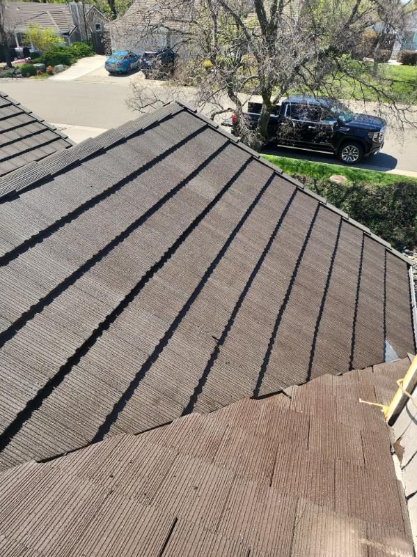 Brown metal tile roof with a view of a street with cars and a tree.
