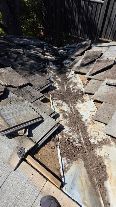 Close-up view of an old roof valley filled with debris and missing shingles, likely in need of repair.