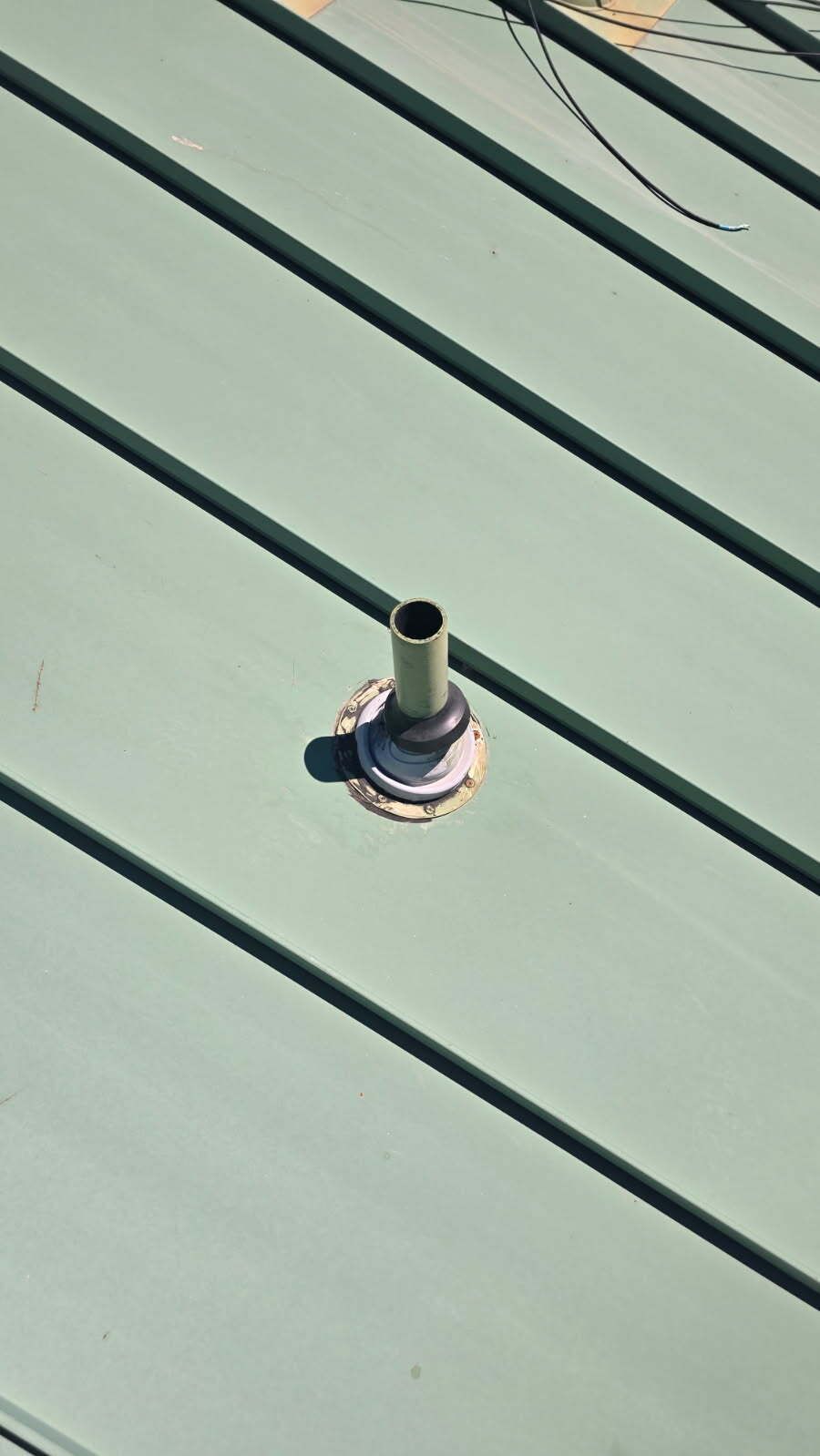 Vent pipe on a green metal roof.