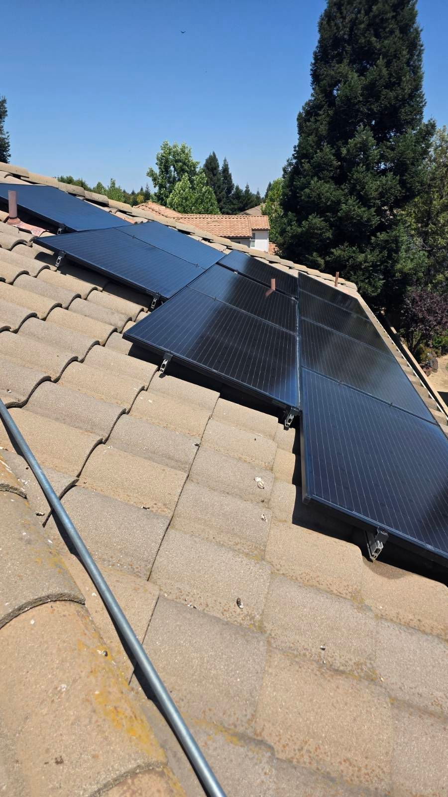 Solar panels installed on a tiled roof, sunny day.