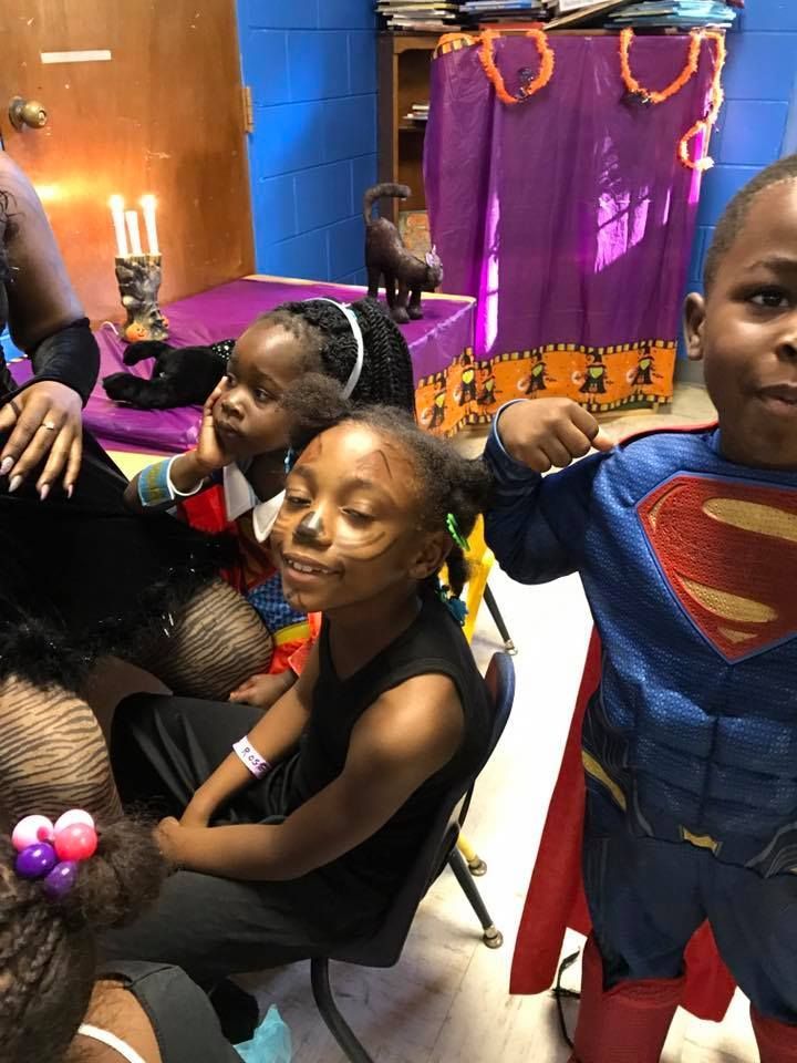 A boy in a superman costume is standing next to a girl in a witch costume.