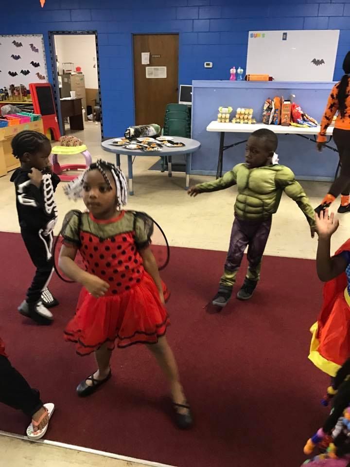 A group of children in costumes are dancing in a room.