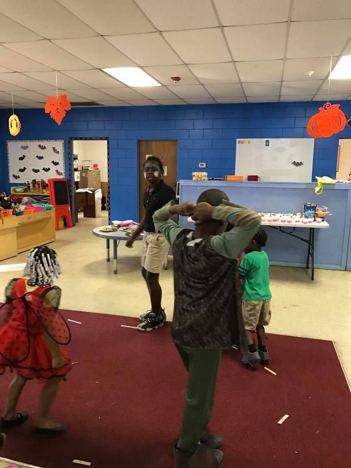 A group of children are dancing in a room decorated for halloween.