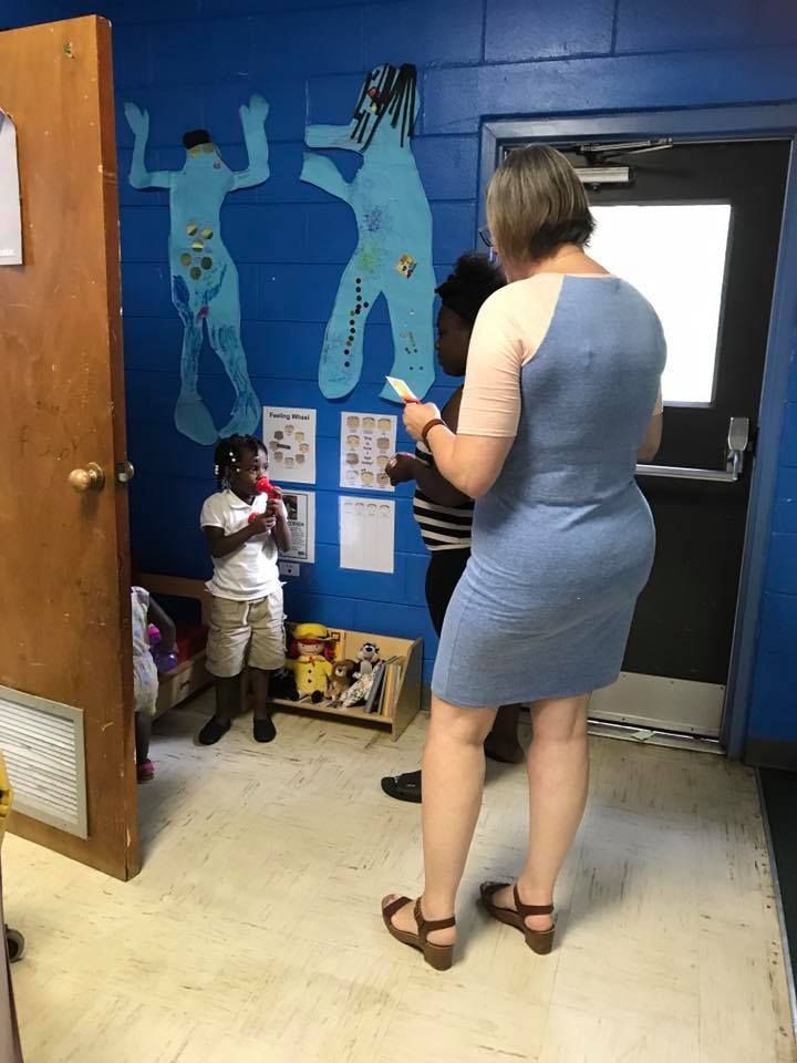 A woman in a blue dress is standing in a room with two children.