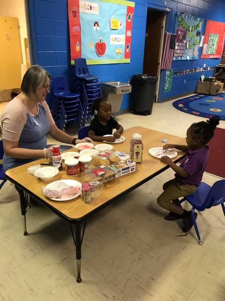 A woman and two children are sitting at a table eating food.