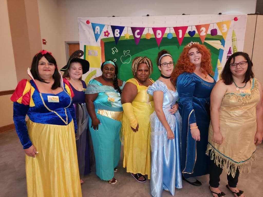A group of women dressed in princess costumes are posing for a picture.