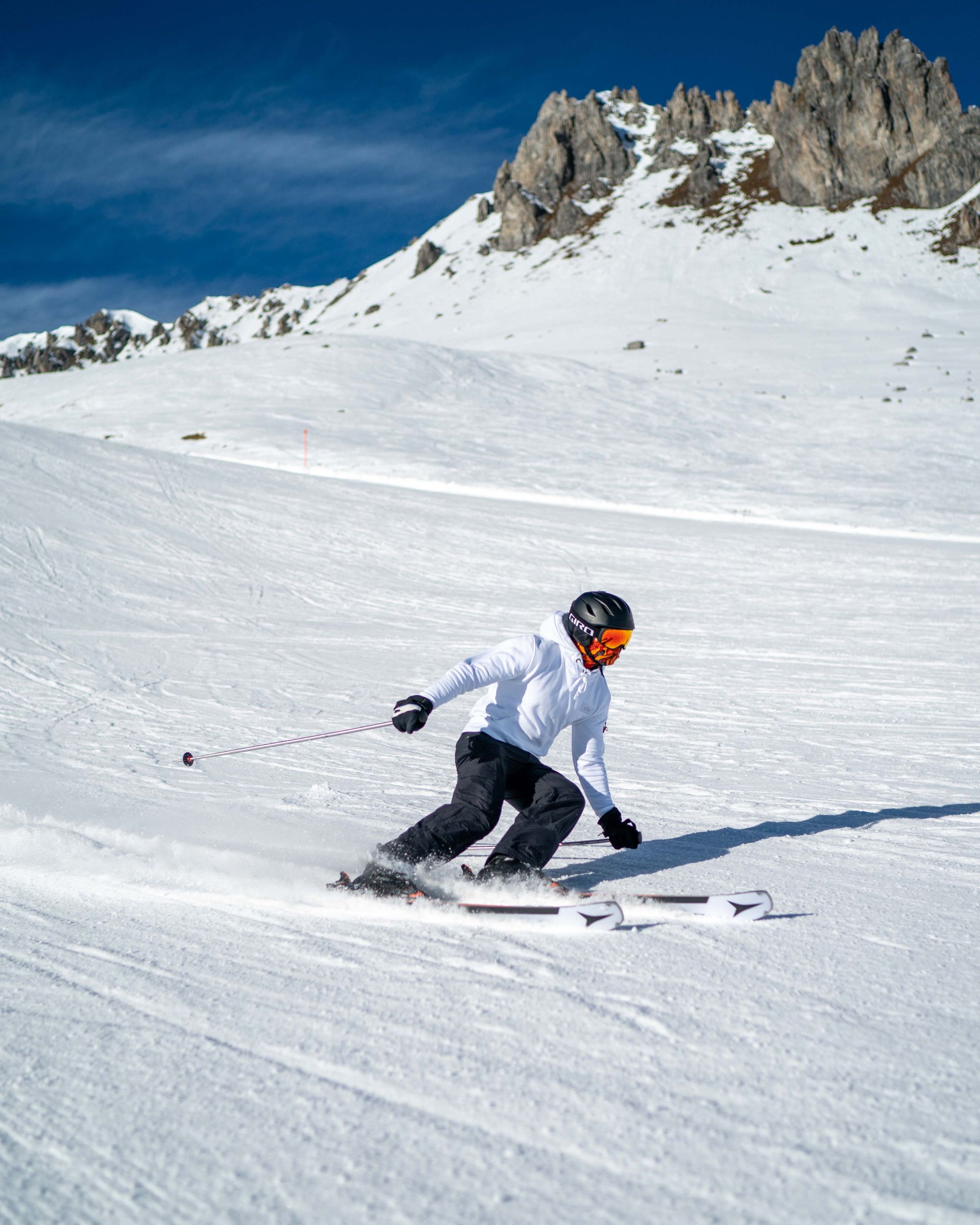 Eine Person fährt mit Skiern einen schneebedeckten Hang hinunter.