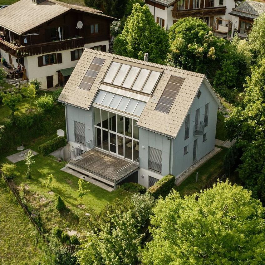 Eine Drohnenaufnahme eines Hauses mit Sonnenkollektoren auf dem Dach. 