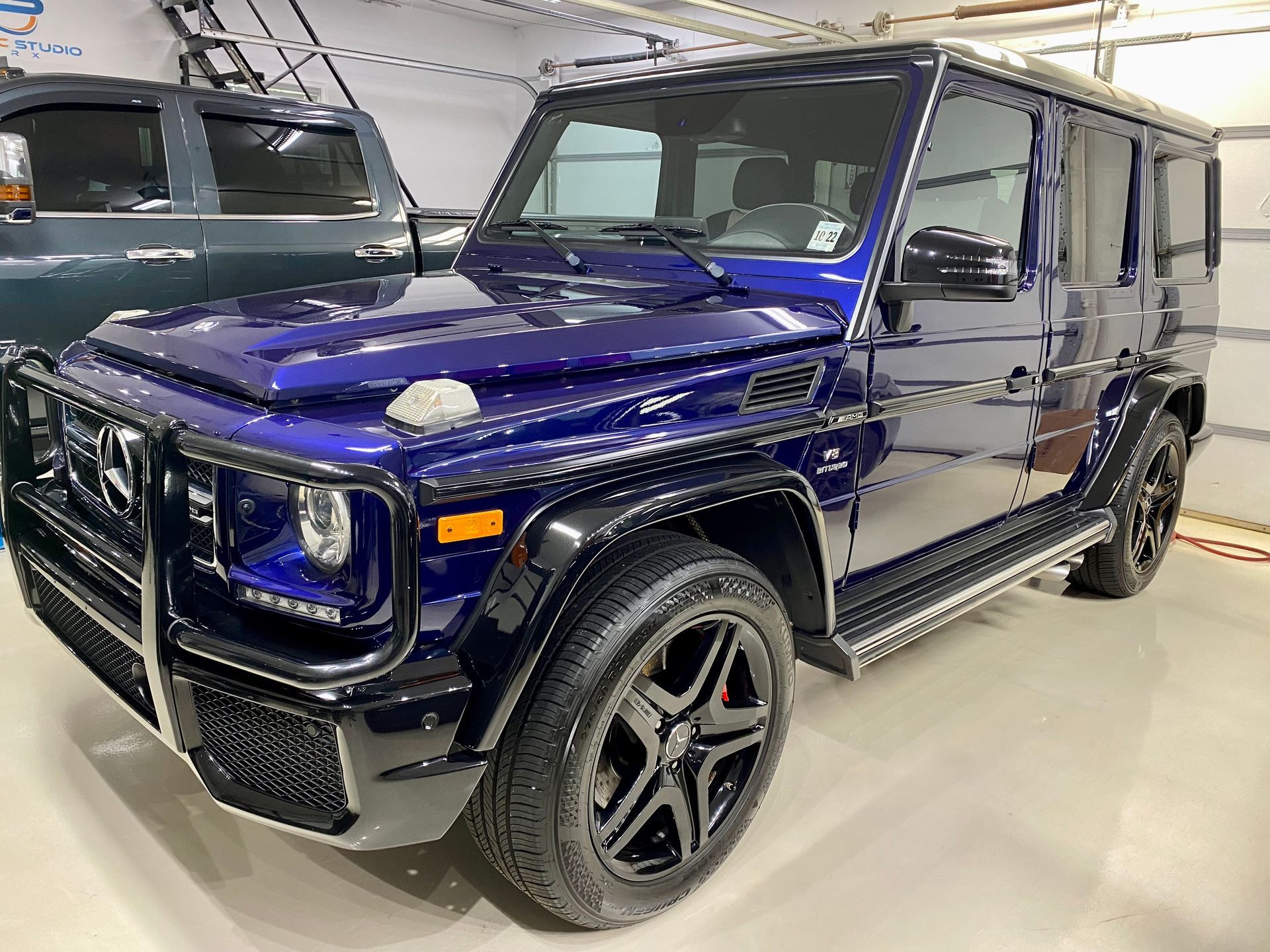 Dark blue Mercedes-Benz G-Wagon parked inside. Black grill, wheels, and trim.