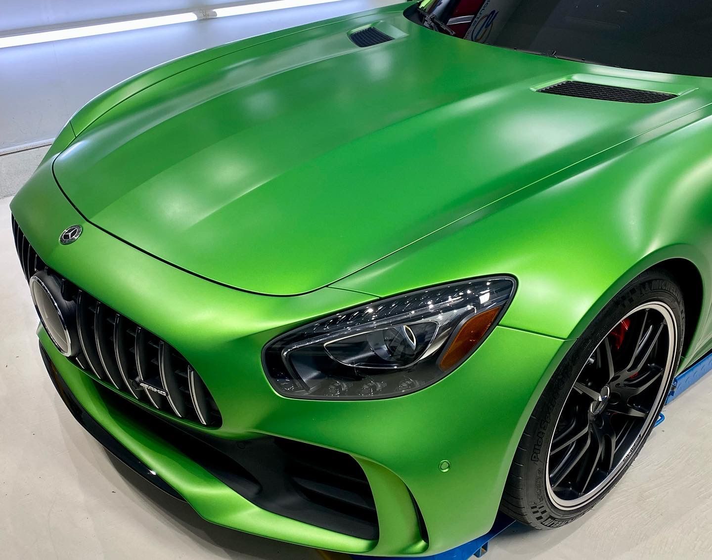 Green Mercedes-AMG GT sports car with a matte finish, black wheels, and red brake calipers.