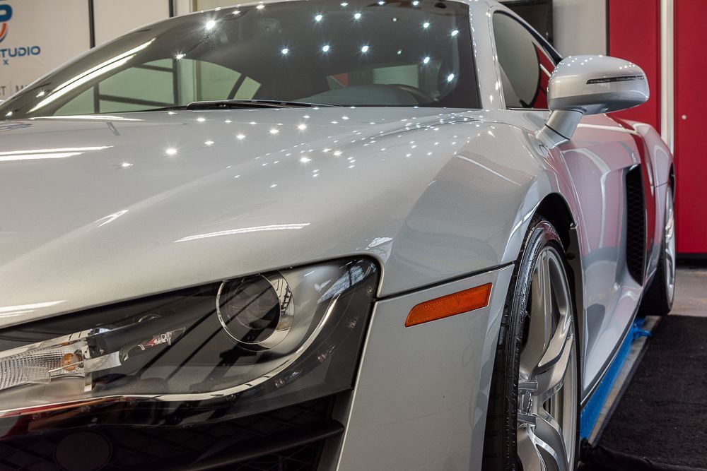 Silver Audi R8 sports car, side view, parked indoors.
